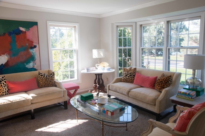 two sofas with large abstract painting and glass coffee table in small living room showing furniture arrangement