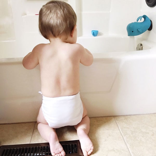 baby kneeling at bathtub