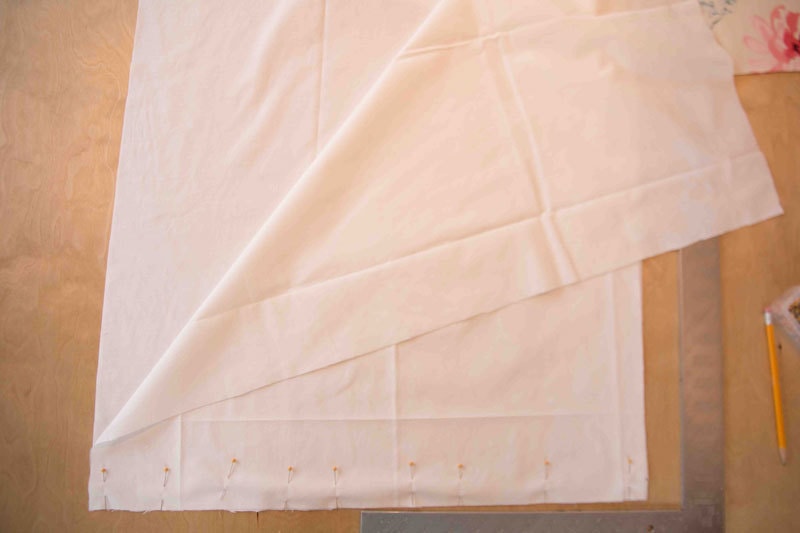 how to make roman shades with picture of fabric being stitched together with pins and a straight edge on table