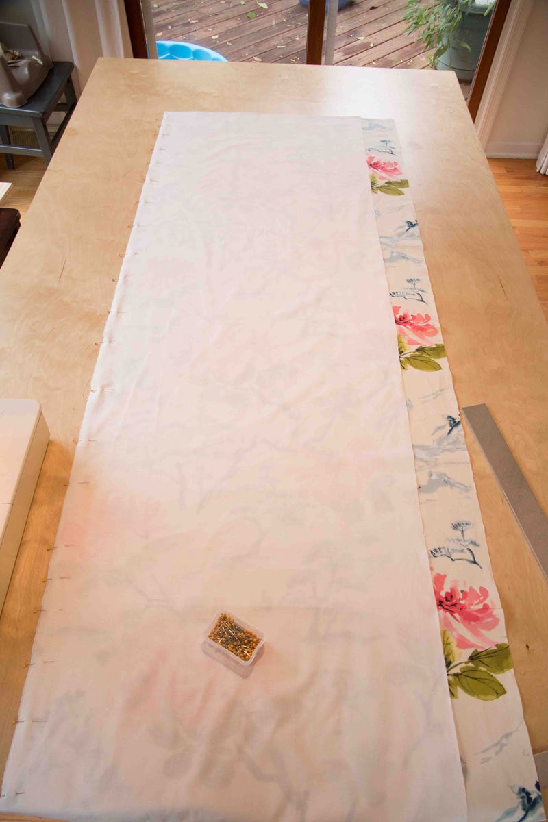 making your own roman shade with fabric and fabric liner on a kitchen table with pins