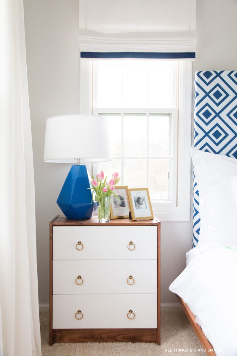 wood and white ikea bedside table with blue and white curtains and blue and white headboard