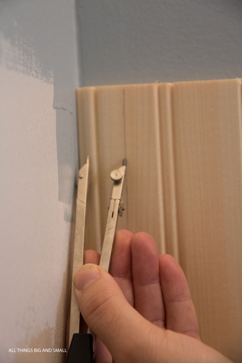 using a compass to scribe wood beadboard planks into uneven corner of bathroom