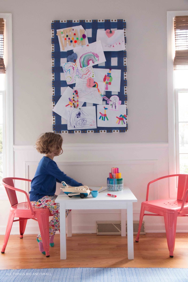 Girl drawing play table under kids art bulletin board in playroom decor makeover