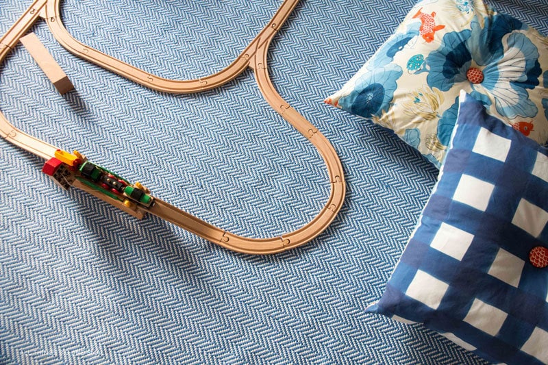 wooden train and DIY floor pillows on playroom rug--great playroom decor ideas for a playroom makeover