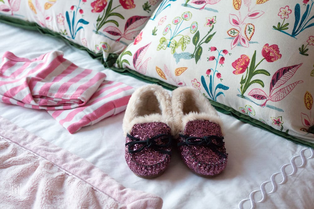 pink pajamas pink glitter slippers on girls bed in shared girls bedroom