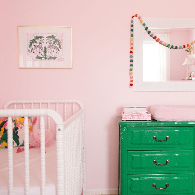 pink nursery with decorative garland and green dresser