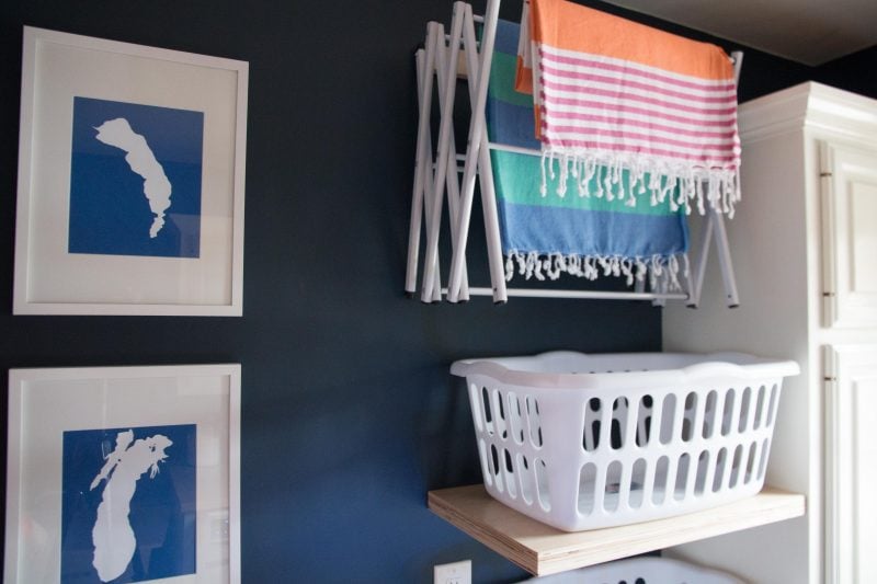 navy blue laundry room with nautical artwork turkish towels and floating shelves with laundry baskets with walls painted benjamin moore hale navy paint color