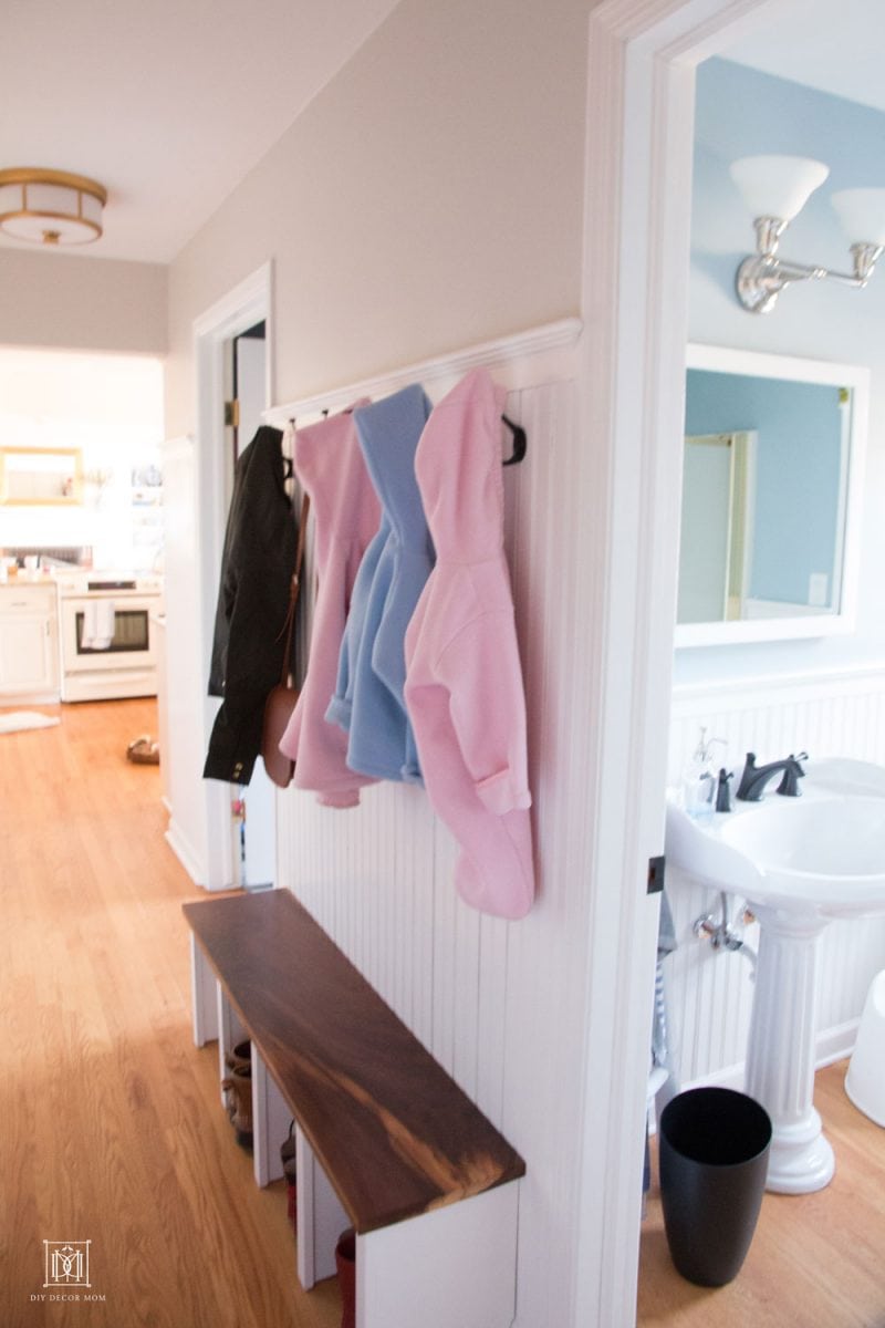 narrow hallway with small mudroom bench coat hooks and beadboard trim