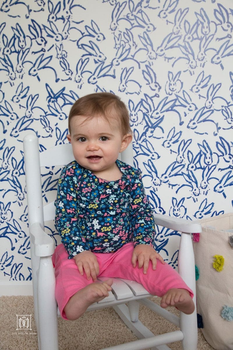 cute baby girl in blue and white nursery wearing blue bodysuit and pink baby pants