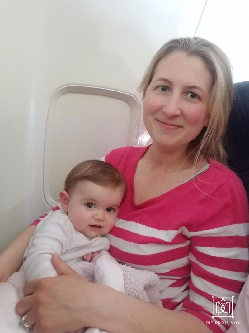 traveling with baby diaper bag checklist--picture of woman holding baby on airplane