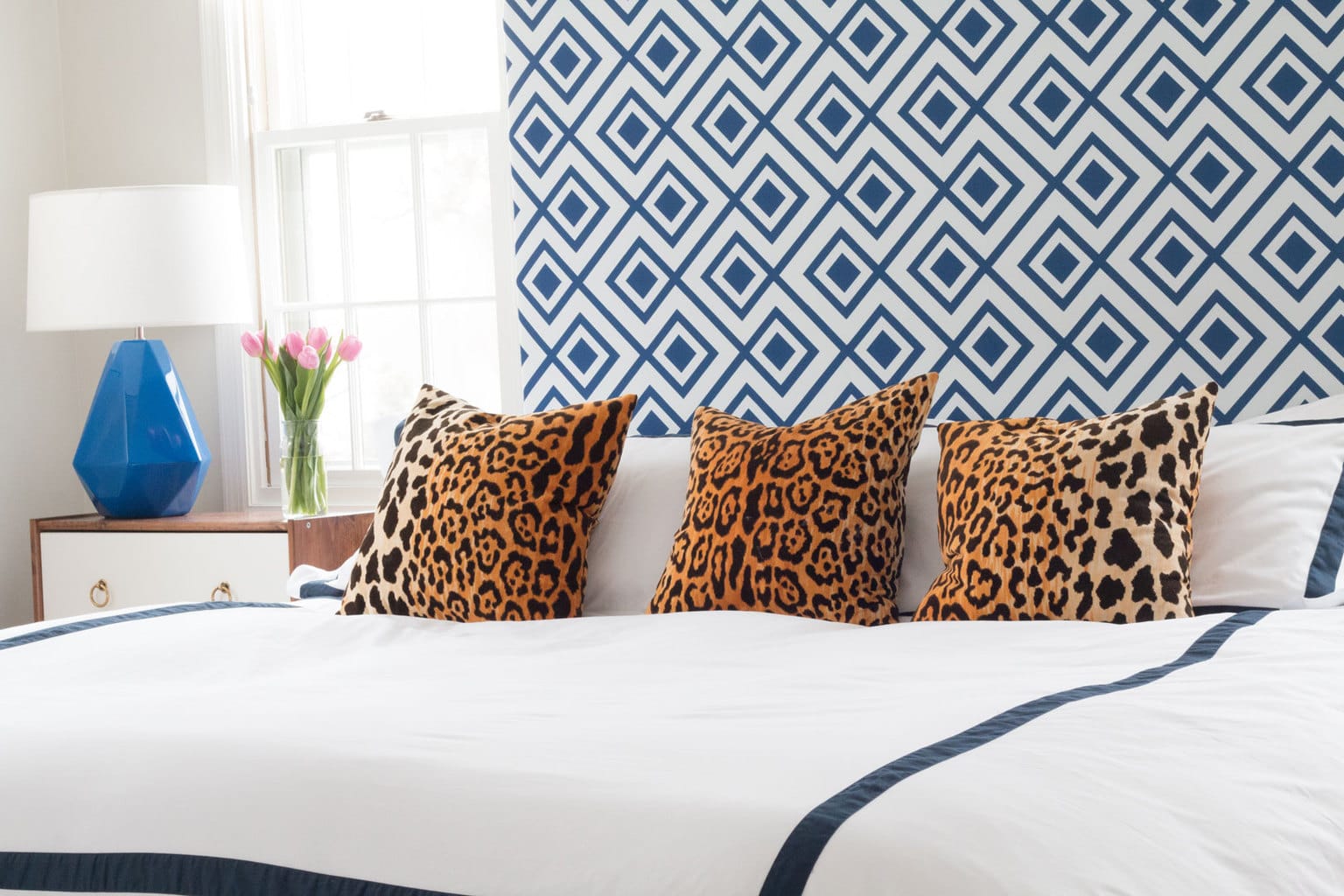 blue and white headboard with blue and white bedding and leopard throw pillows