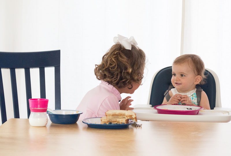 girl and baby girl laughing at dinner table 