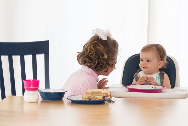 girl and baby girl laughing at dinner table