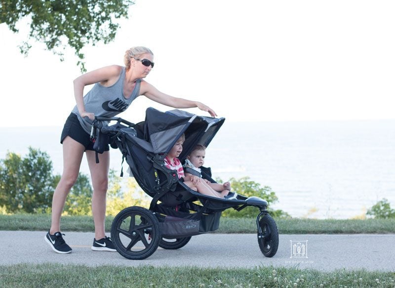 woman adjusting shade on double jogging stroller showing things to look for in best double jogging strollers