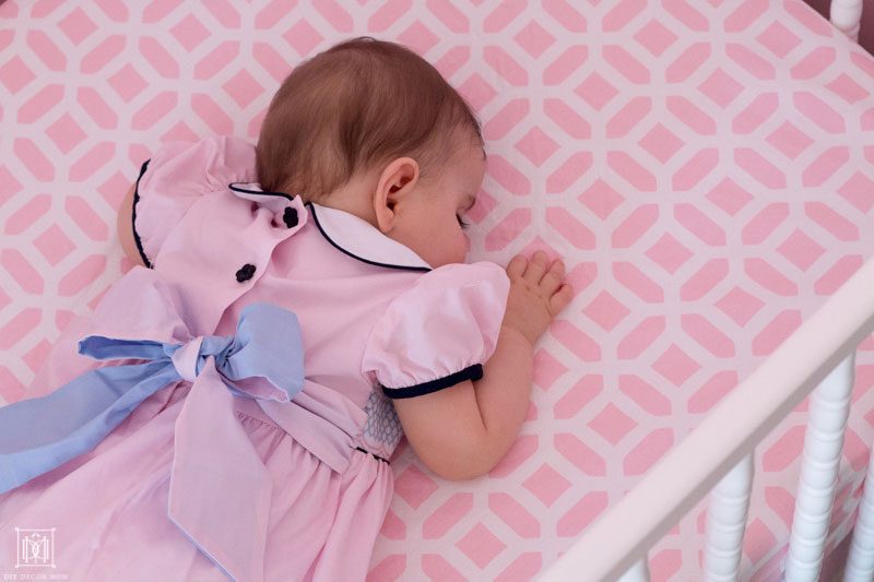 breastfed baby sleeping in a crib with pink dress