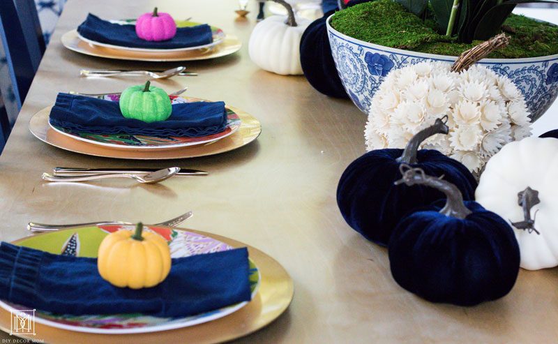 tablesettings with gold chargers navy napkins and colorful pumpkins