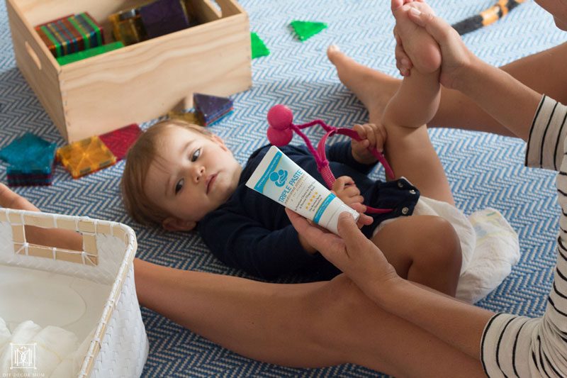 mom changing baby's diaper with triple paste ointment