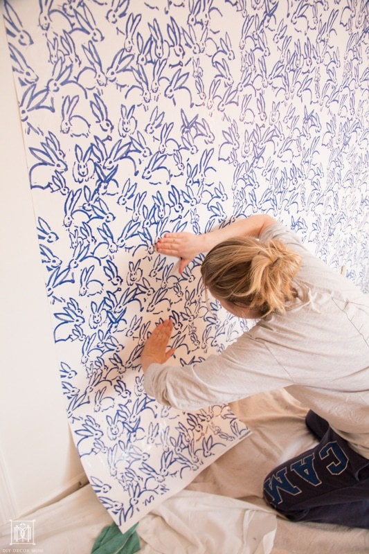 woman hanging wallpaper and smoothing out air bubbles with her hands