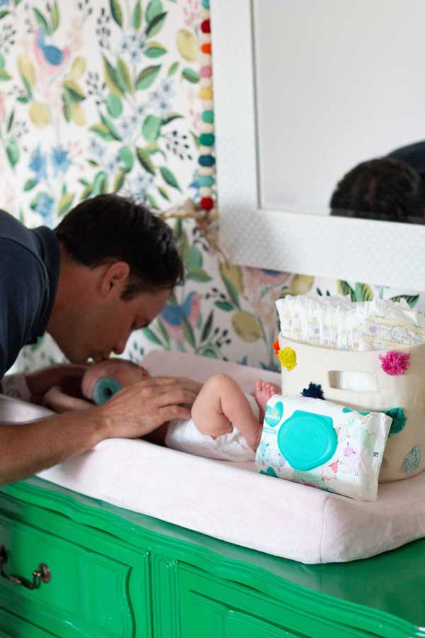 dad changing newborn diaper and kissing on head