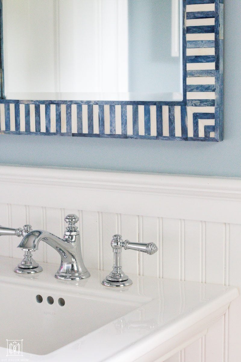 blue and white mirror on top of small pedestal sink in small bathroom with tips to make small bathrooms look big