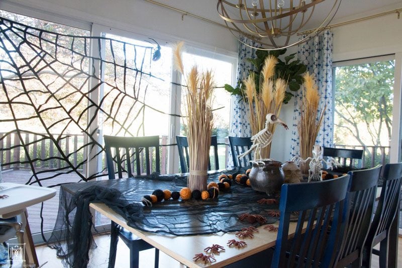 table with halloween decorations and spider web, skeletons, and skulls