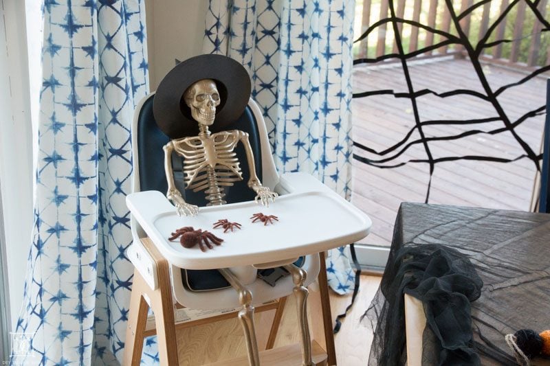 gold skeleton sitting in high chair with halloween table decor