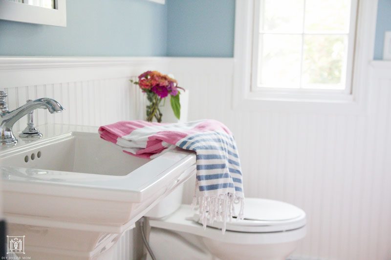 white pedestal sink and toilet in white beadboard small bathroom- 9 ways to make a bathroom seem bigger