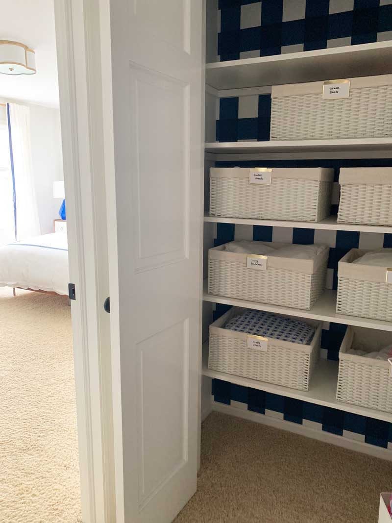 organized linen closet with white baskets