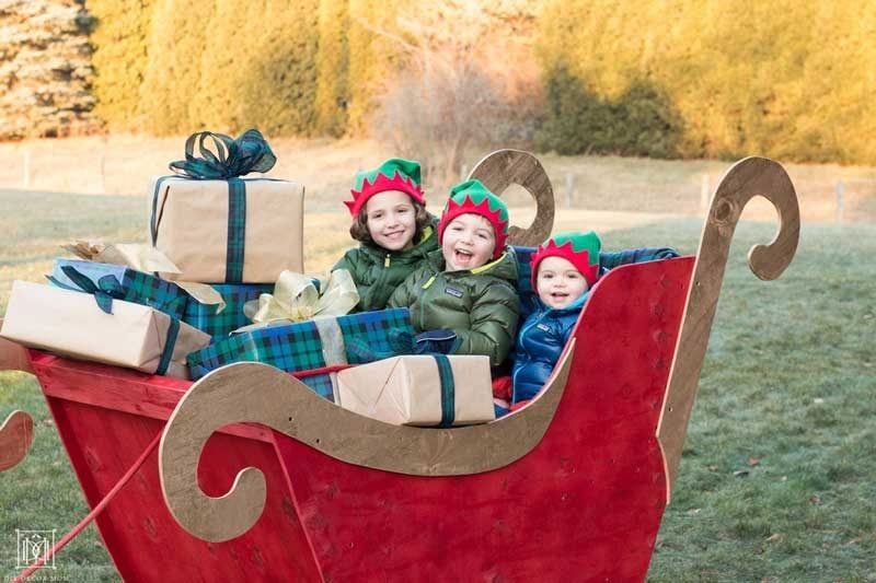 kids sitting in a diy santa sleigh in yard