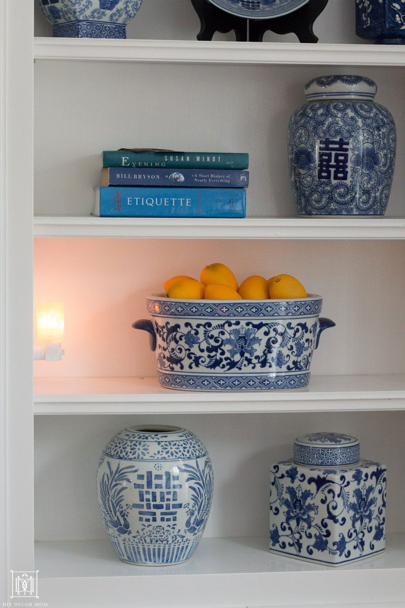 salt lamp plugged into bookshelf with blue and white pottery