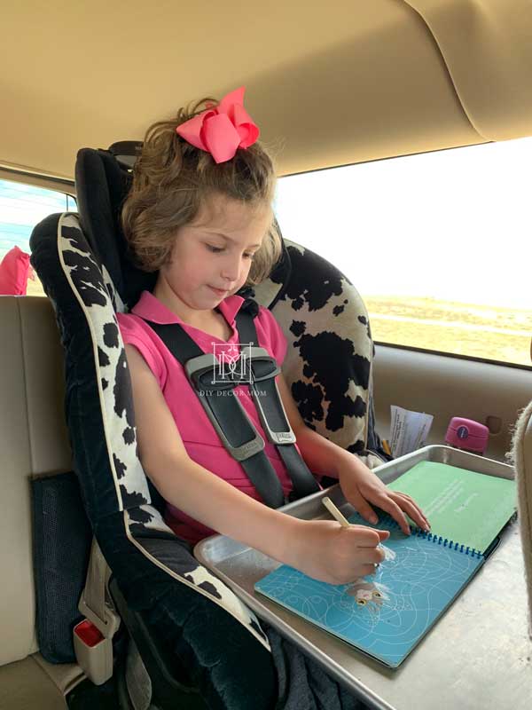 kid in carseat working on road trip activities