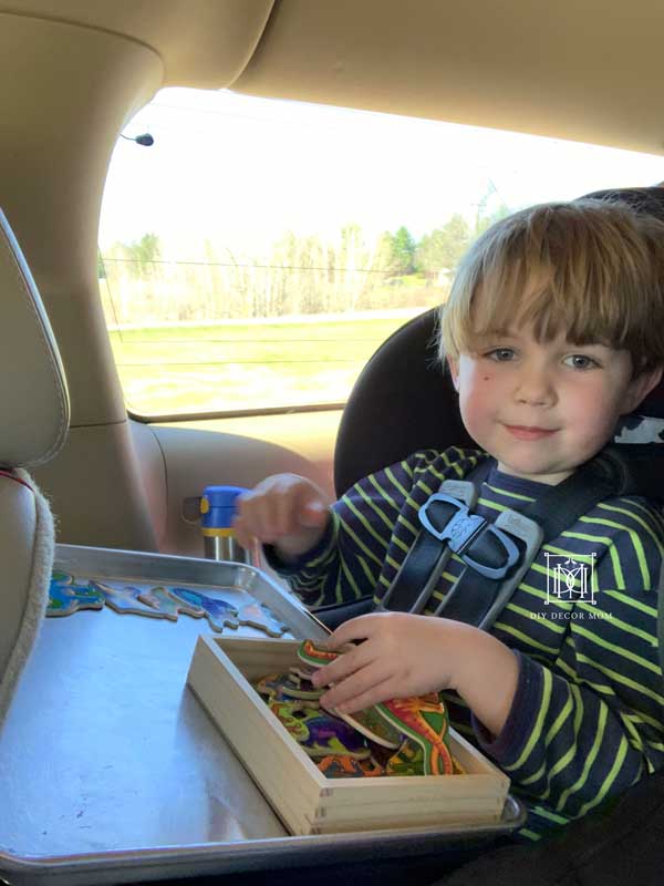 toddler boy playing with magnets on road trip with family