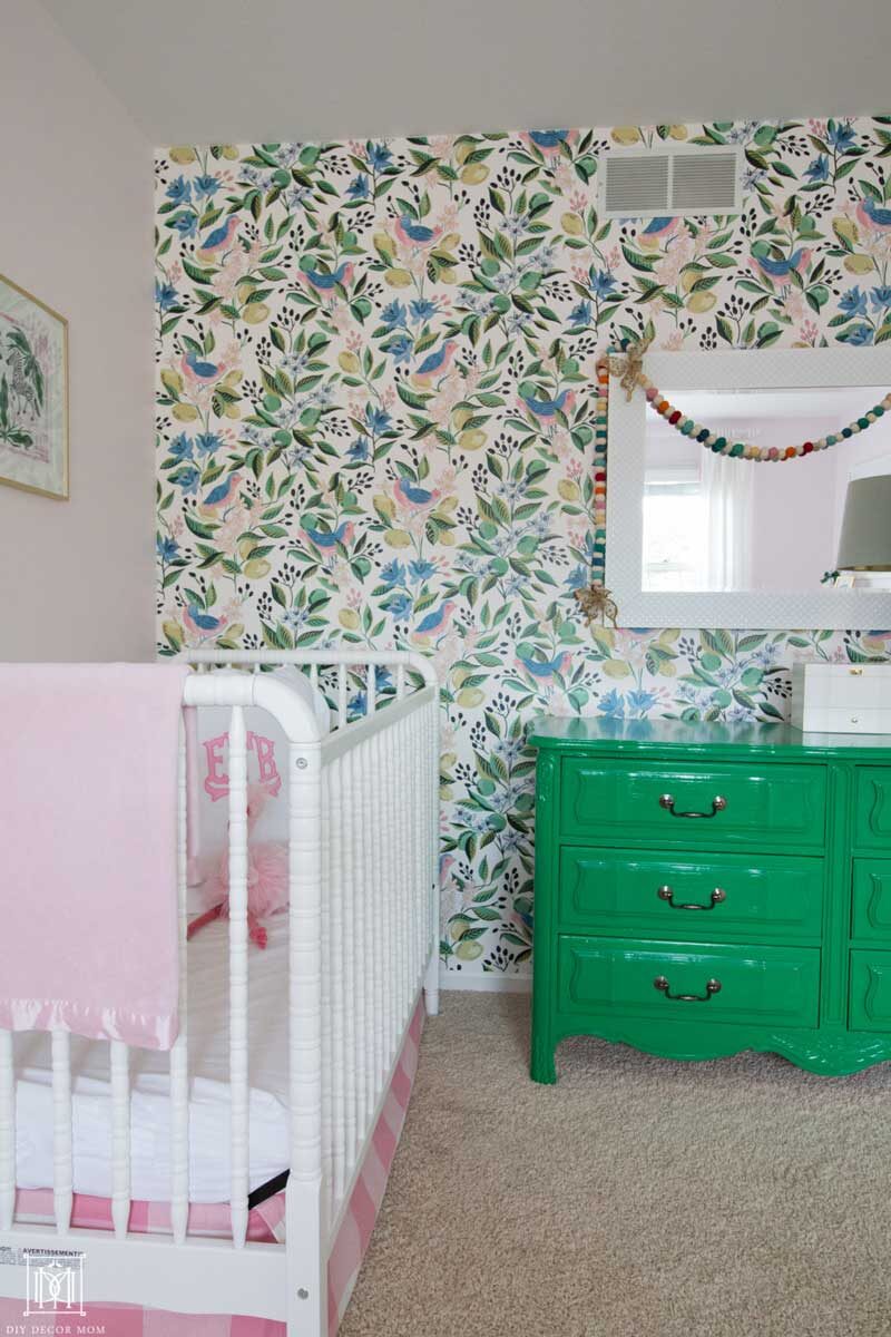 crib with wallpaper accent wall in girls bedroom