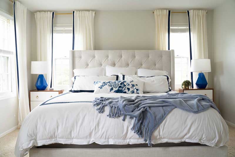 beautiful master bedroom upholstered bed with blue and white linens