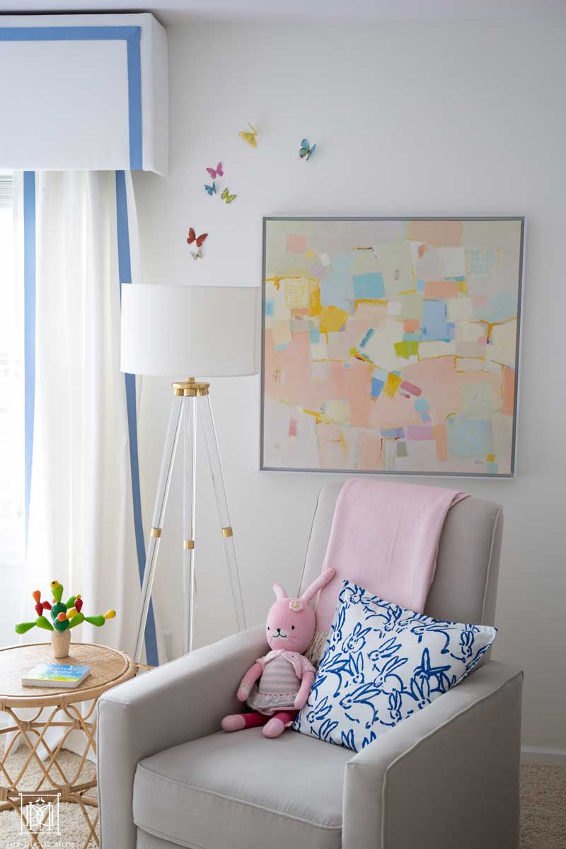 rocking chair glider in nursery with abstract artwork and white walls