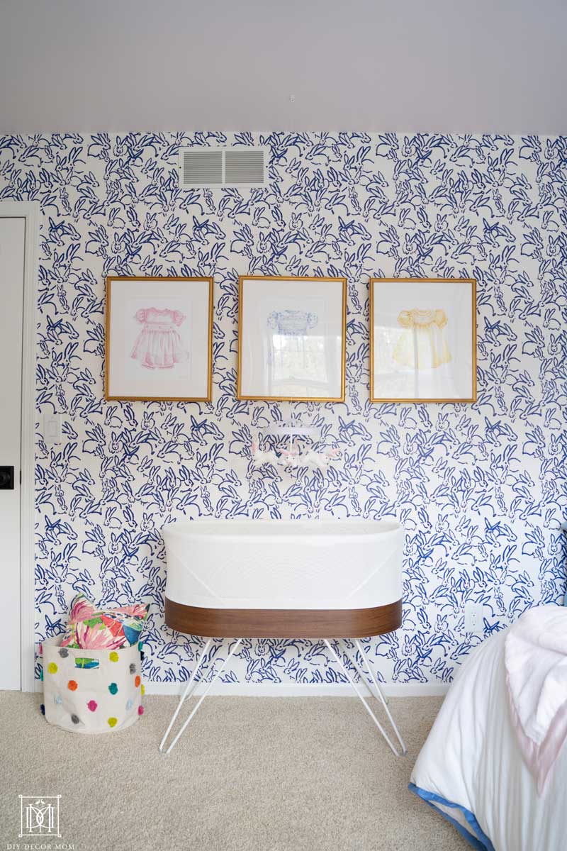 blue and white wallpaper accent wall in baby girl room with pink ceiling and pictures