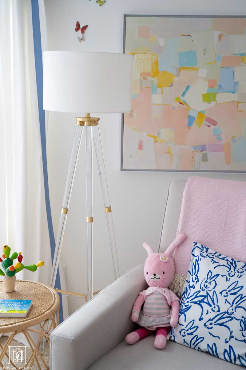 baby girl room decor with rocking chair and lucite lamp and abstract painting on white walls