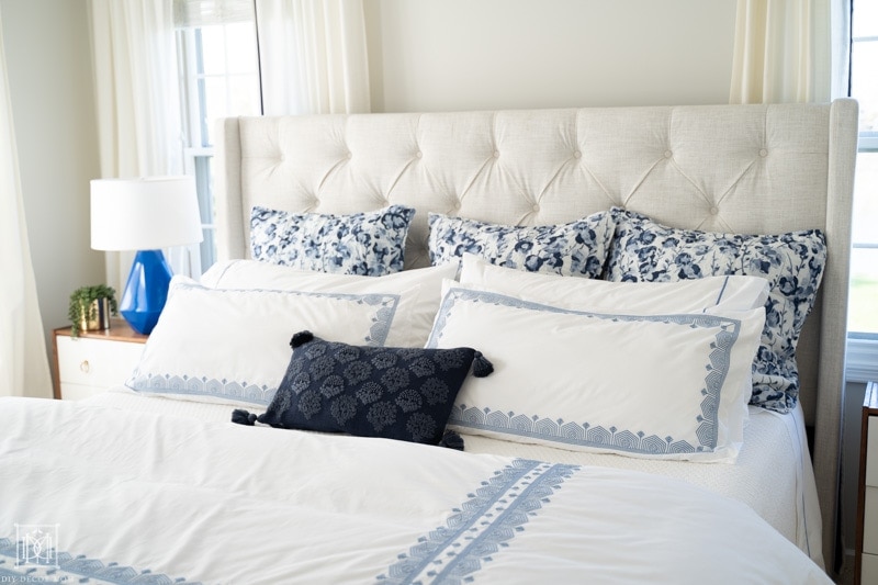 blue and white bedding on king size bed with duet cover, gray walls, and white curtains