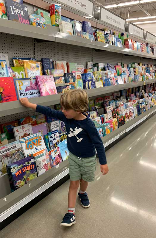 boy in aisle at meijer shopping for books