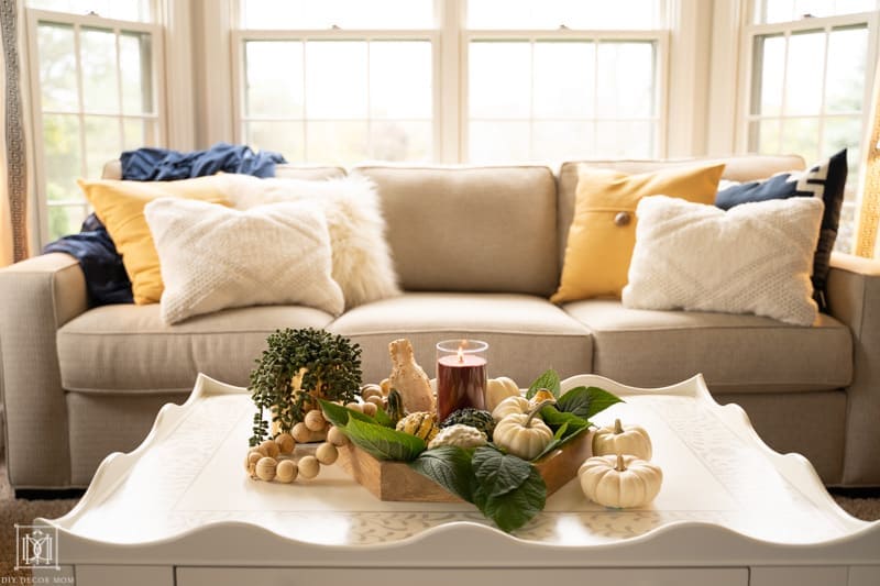 seasonal vignette with hygge tablescape and candles, natural textures, wood tones, and cozy pillows on couch