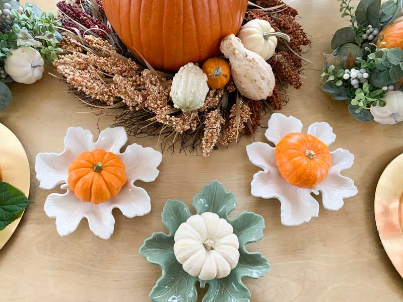 large pumpkin with wreath around it and small gourds