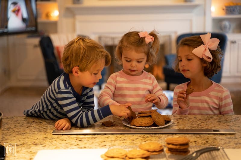 kids at kitchen counter eating warm baked chocolate chip cookies