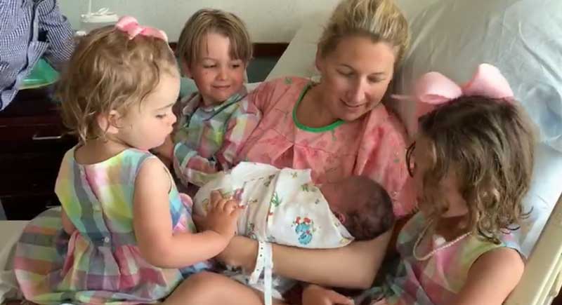 postpartum mom with big siblings meeting new baby at hospital
