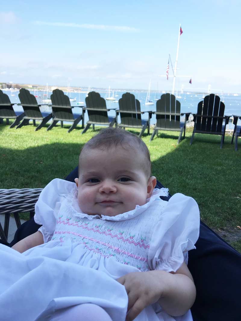 baby on dad's lap at yacht club overlooking harbor