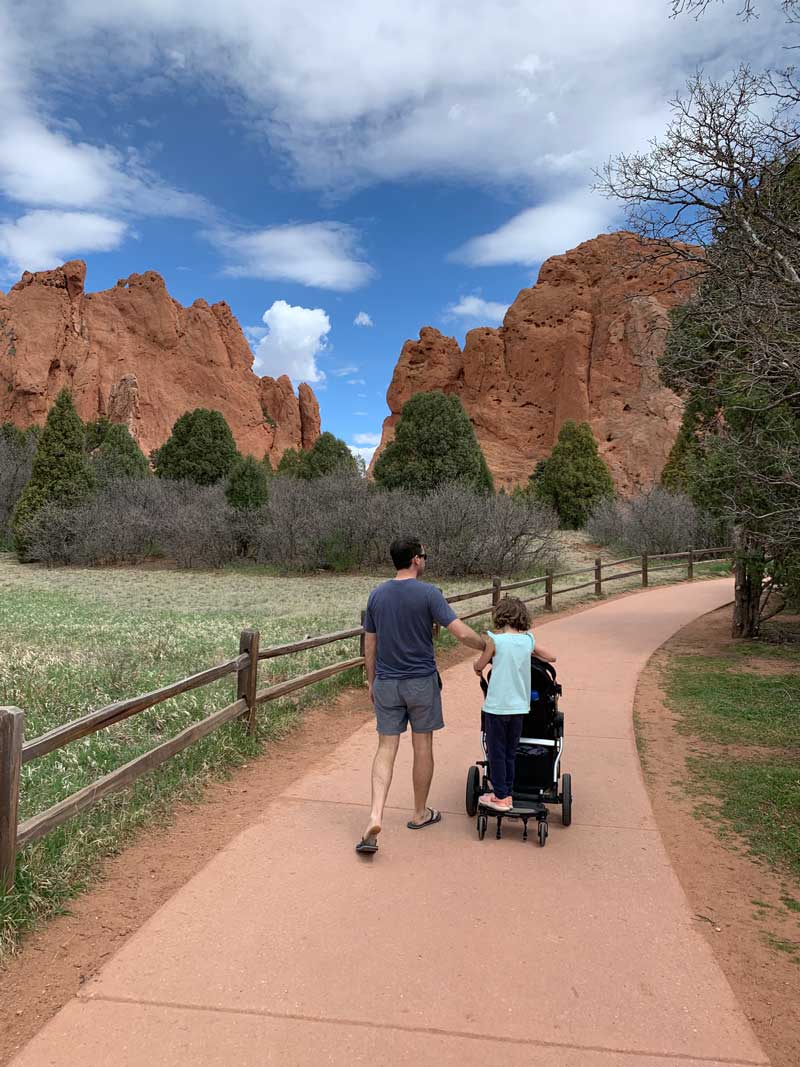 dad pushing stroller with 6 year old riding on gliding board