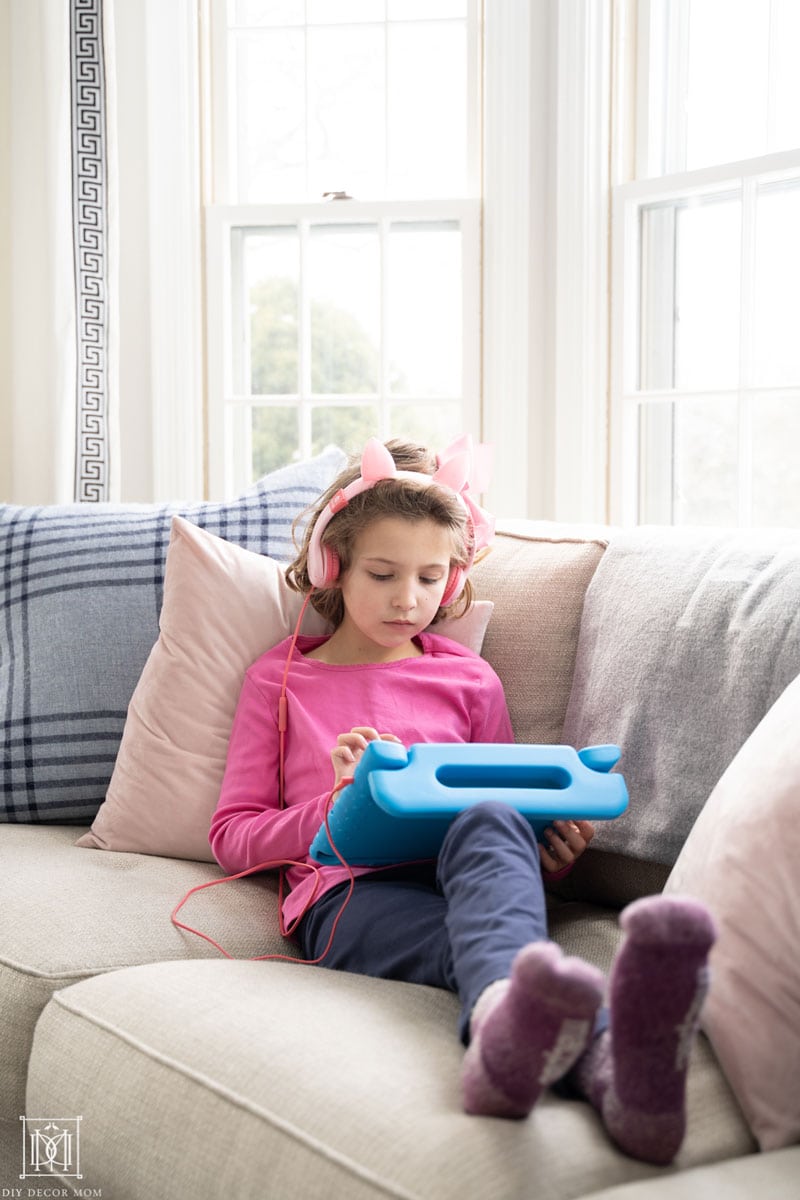 first grade girl reading on ipad on couch