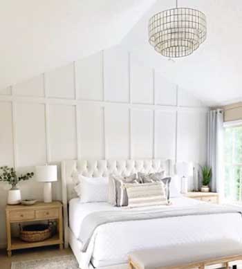 white paneling in master bedroom with comfy upholstered bed 