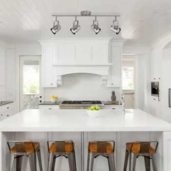 white kitchen range hood with wooden stools on island