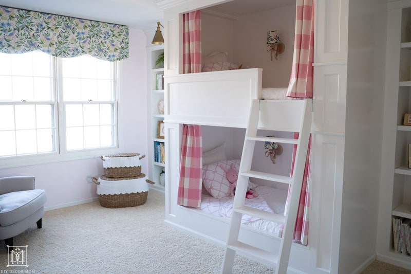 girls built-in bunk beds with traditional panelling and pink and white curtains in shared girls bunk room