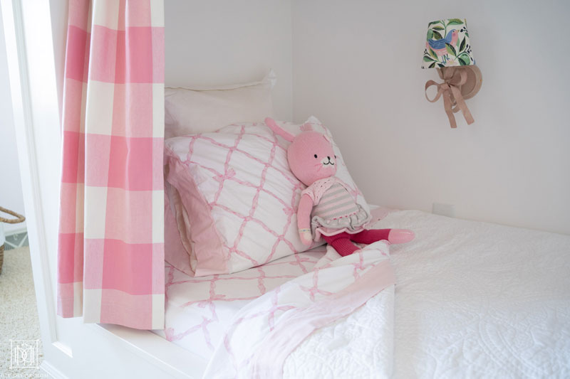 girls bed in shared girls bunk room with fabric covered lampshade and pink and white bedding